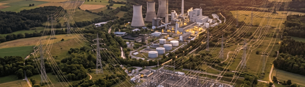 Power plant with cooling towers and electrical substation with transmission lines at sunset